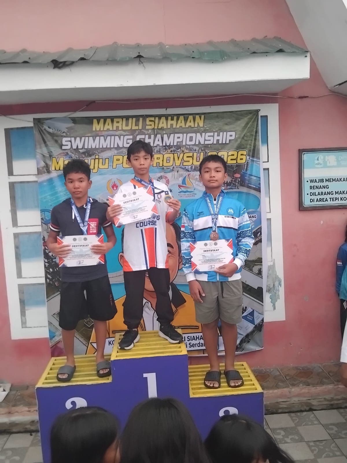 Atlet muda mengangkat medali usai lomba renang